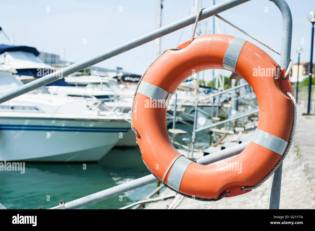 Orange life buoy hanging from a railing at the port. Stock Photo