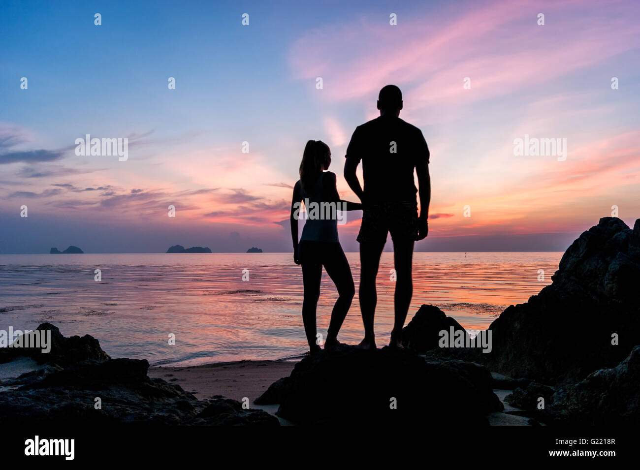 Silhouette young couple standing on the beach holding hands and ...