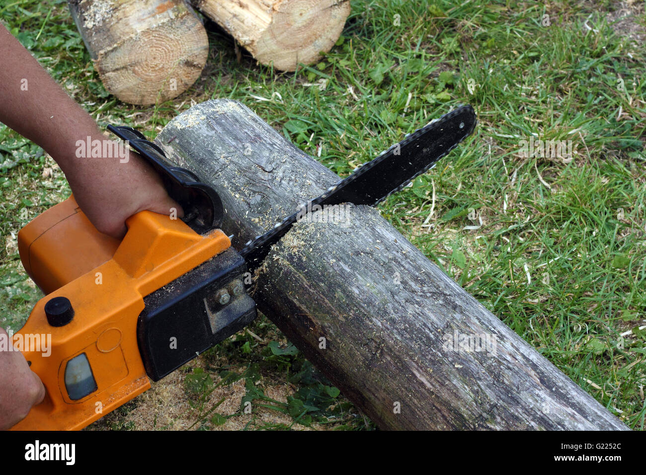 Worker cuts a beam by electric chain saw photo Stock Photo