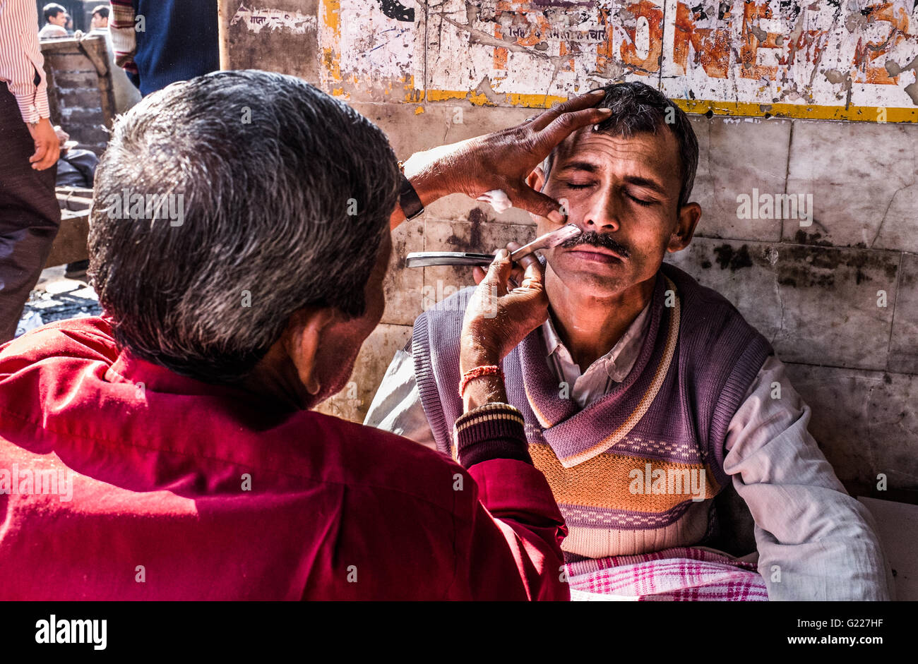 Man having shave from a street barber, Delhi, India Stock Photo