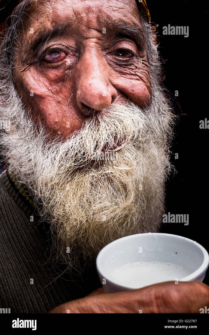 Old man drinking milk on the street in Delhi, India, Stock Photo