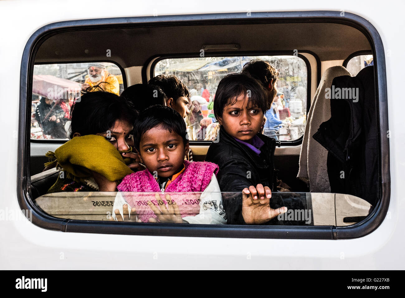 Young children looking out of a car window in Delhi, India. Stock Photo