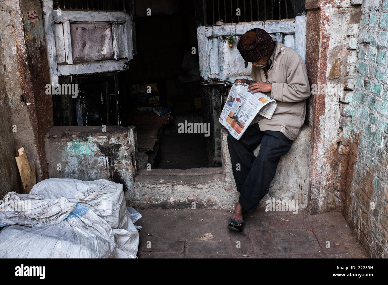 Man reading the newspaper beside his bed in Delhi, India Stock Photo