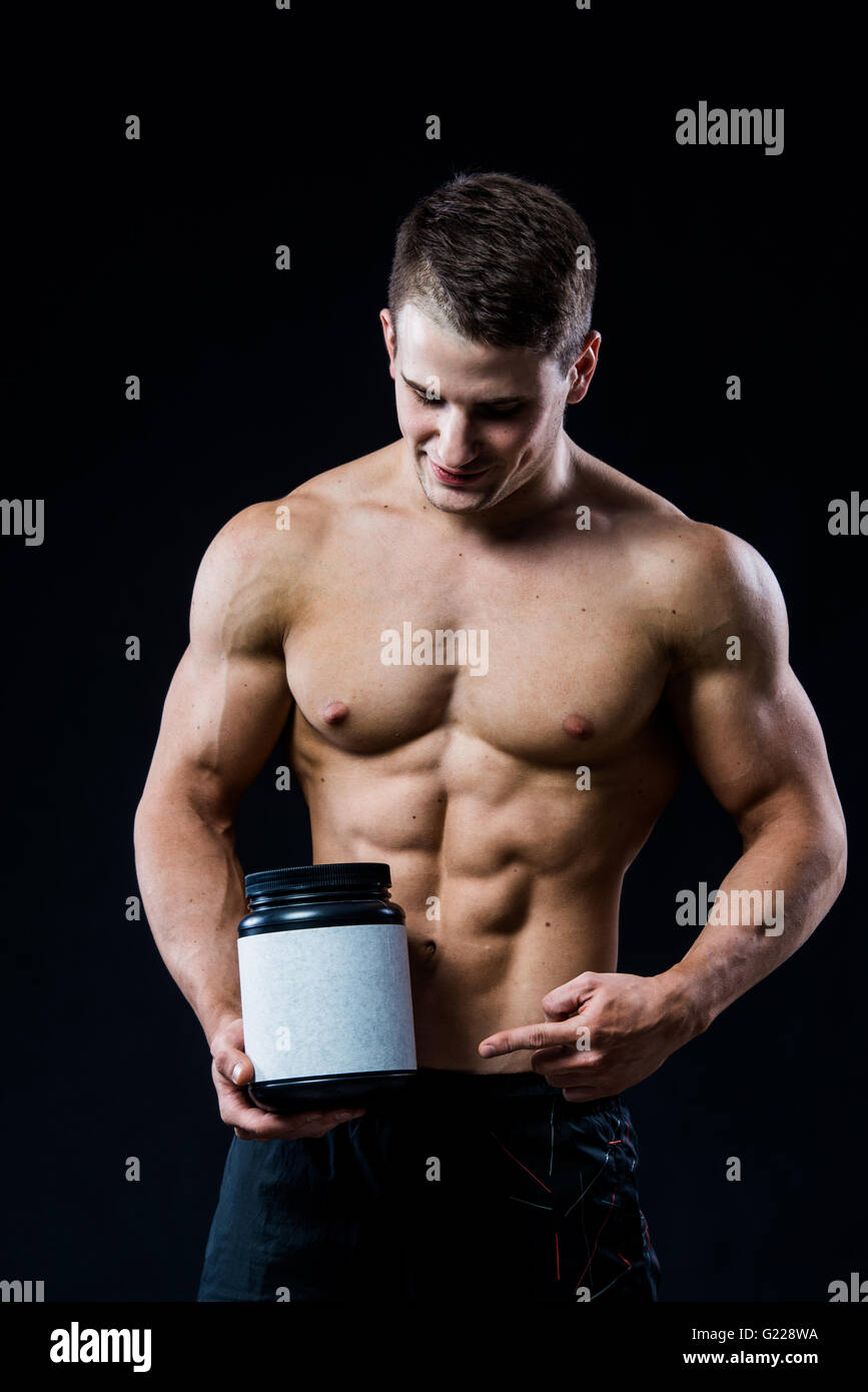 Bodybuilder holding a black plastic jar blank white label whey protein ...