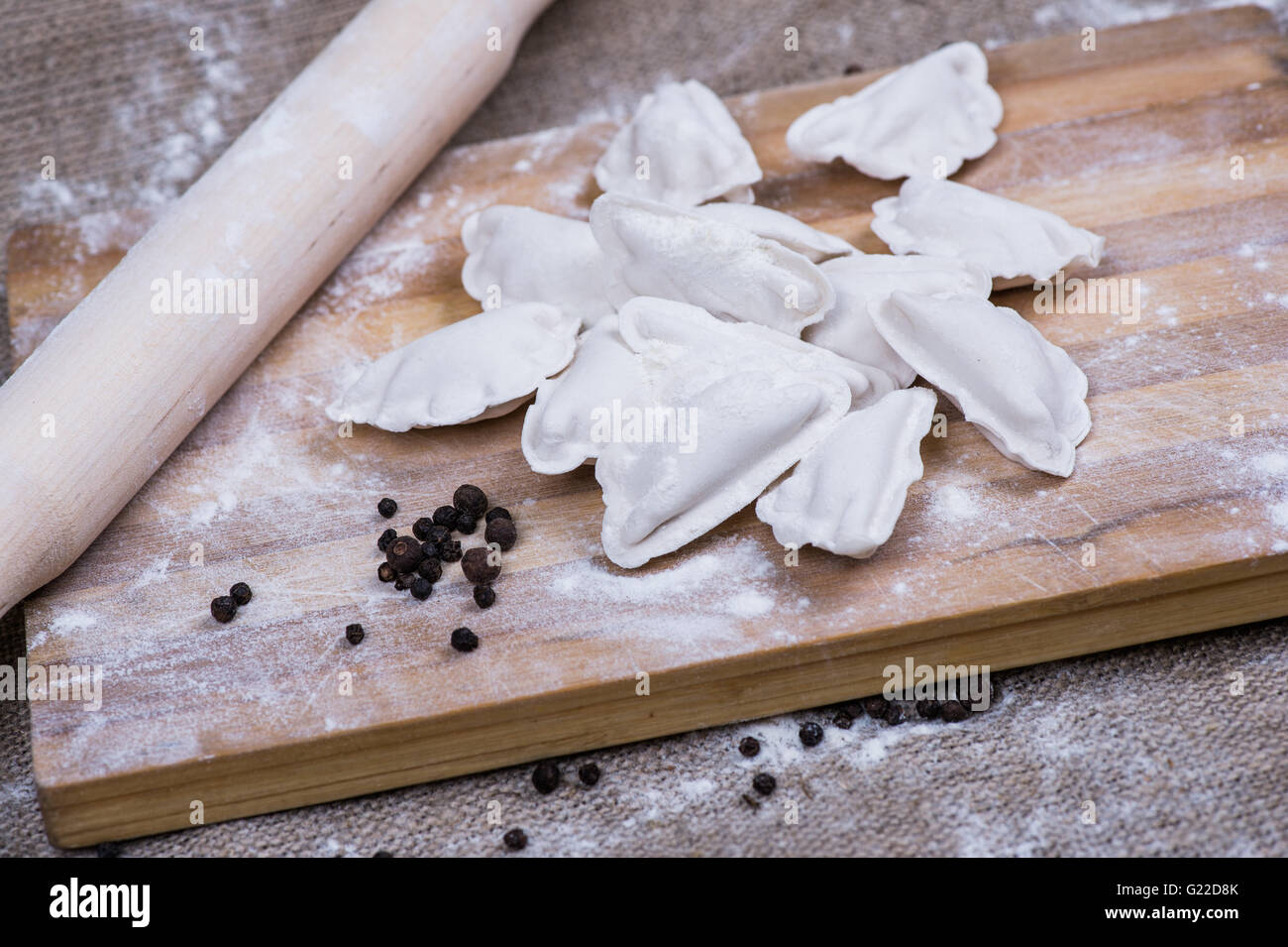 Making of homemade dumplings pastry tortellini or ravioli. Model for home made pasta filled with meat. Preparing organic meal on a wooden desk. Stock Photo