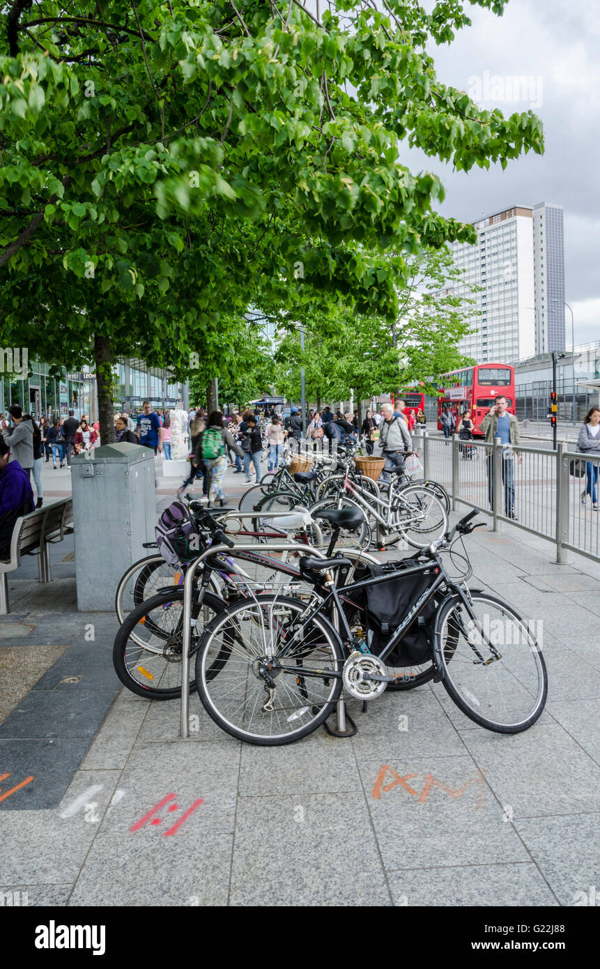 Bicycles at a bicycle rack in Shepherds Bush, London. the pavement has graffiti on it. Stock Photo