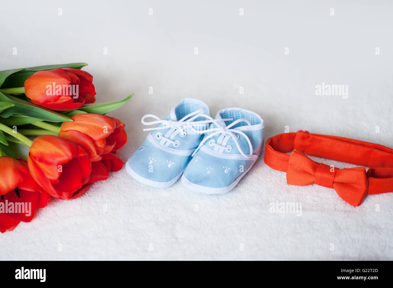 red tulips tie and children blue boots on  white background Stock Photo