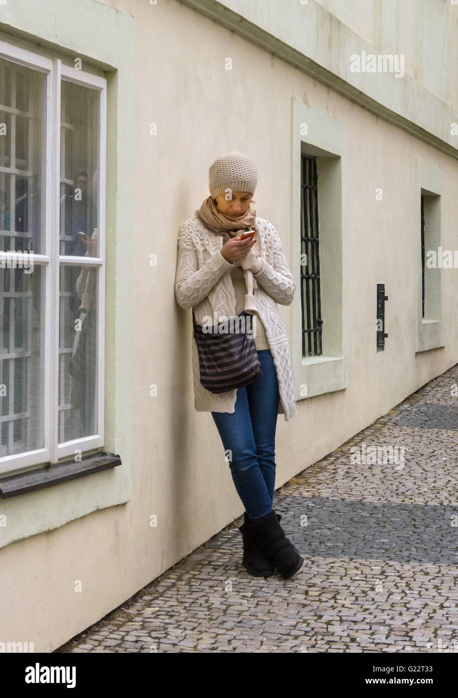 Checking her mail - or texting home. A young female tourist in Prague, Czech Republic pauses to check her email. Prague Castle. Stock Photo