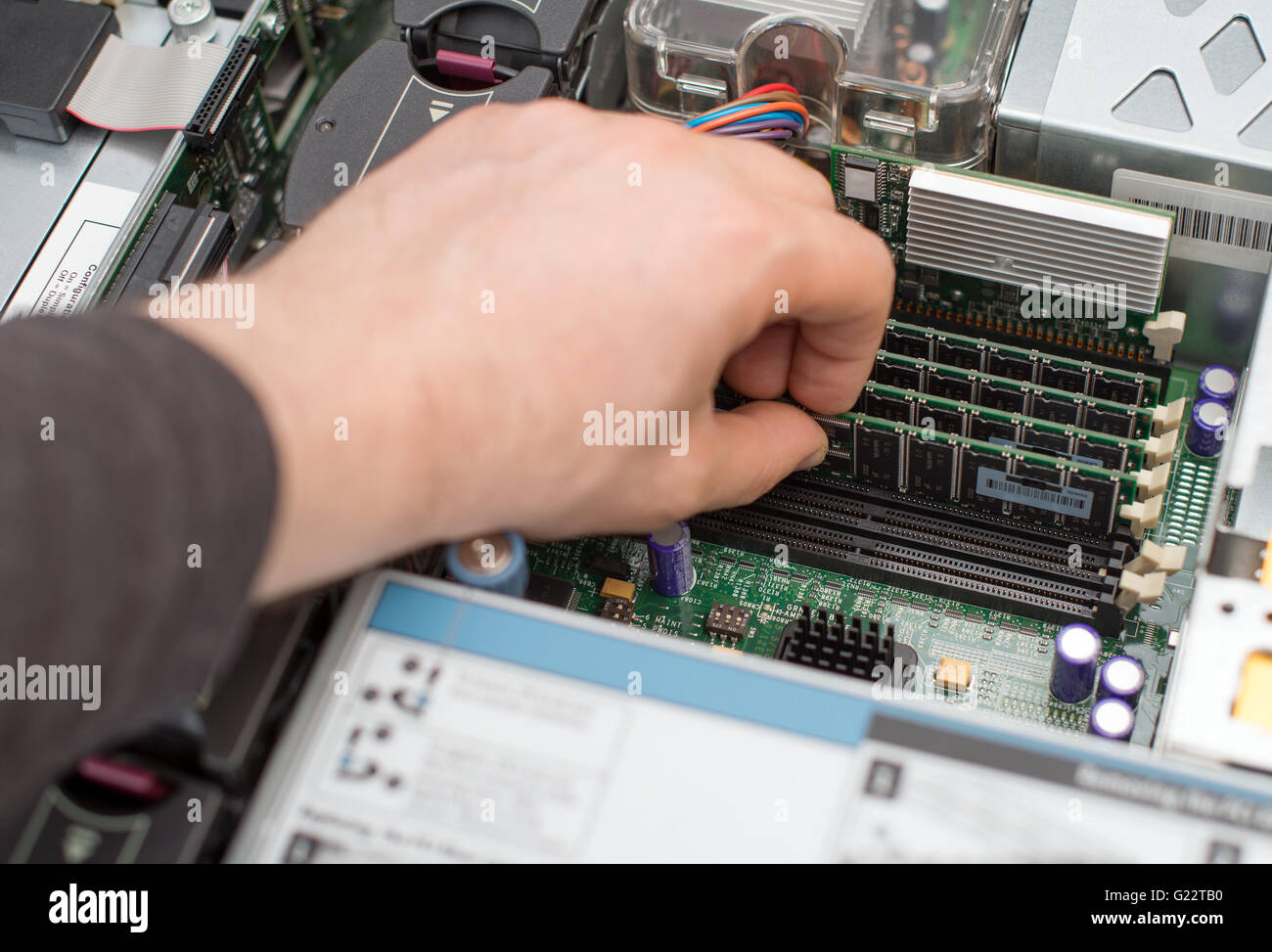 Computer technician installing RAM memory into motherboard. Stock Photo
