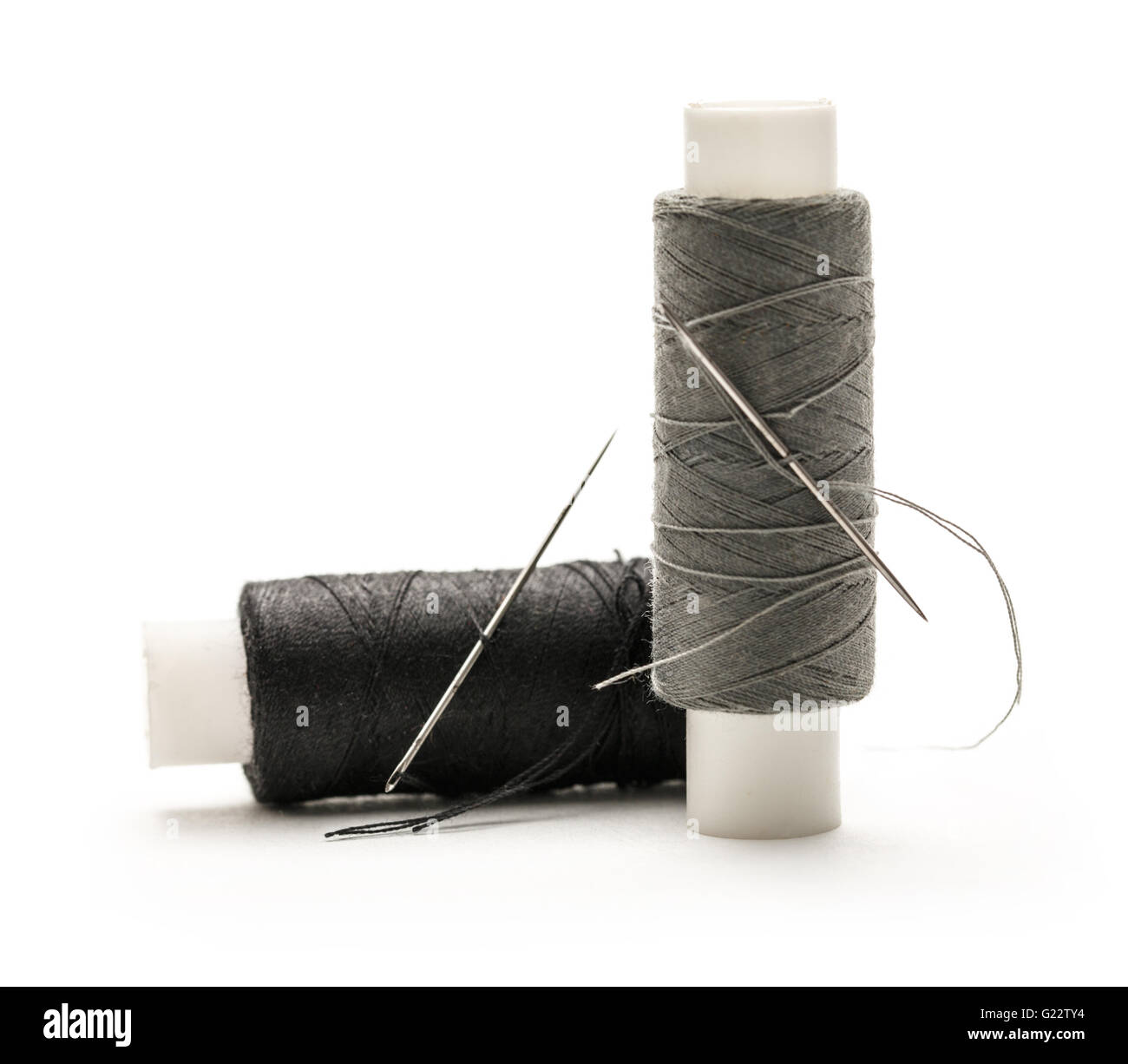 Thread bobbins and needle on white background Stock Photo - Alamy
