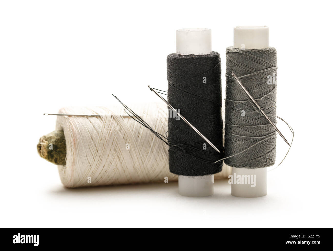 Thread bobbins and needle on white background Stock Photo - Alamy