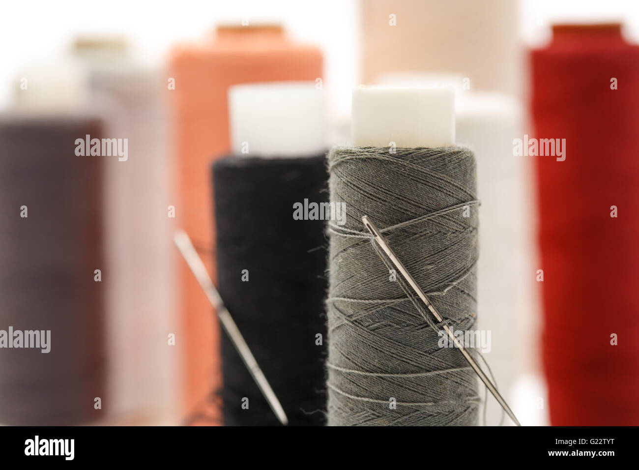 Thread bobbins and needles on white background Stock Photo - Alamy