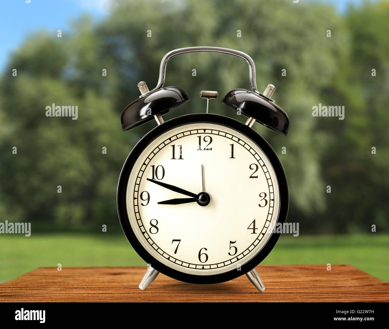 Old fashioned alarm clock on nature background Stock Photo - Alamy