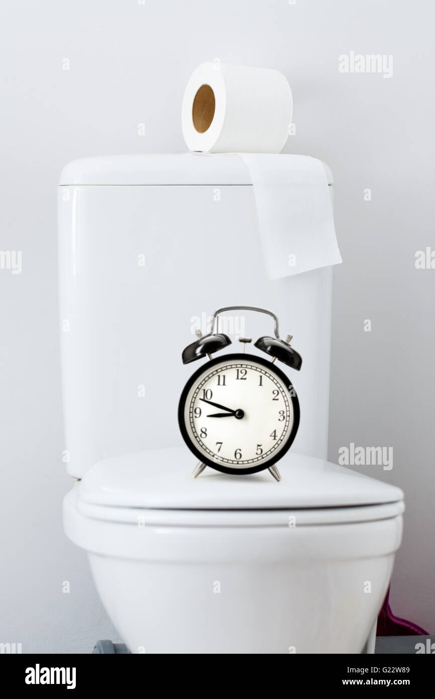Hygienic paper on white toilet tank and alarm clock Stock Photo