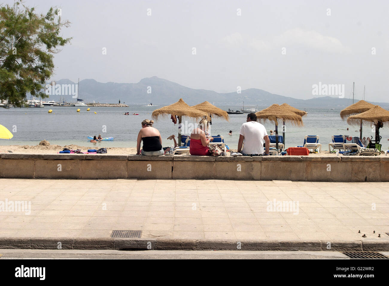 a beautiful picture of tourists sitting on beachfront wall in Palma de Mallorca, Spain, seaside, tourism, holidays, summer Stock Photo