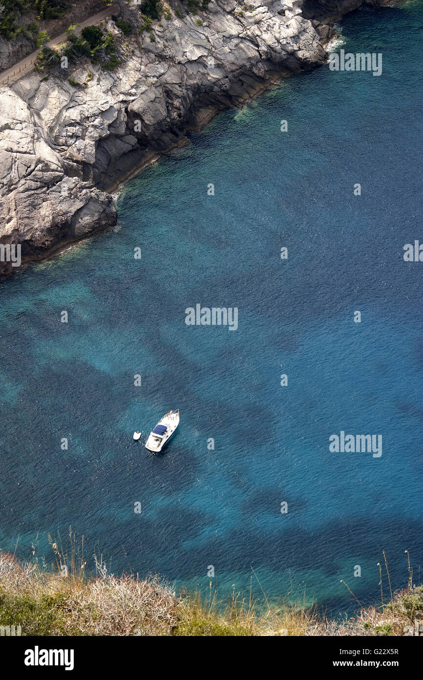 a beautiful picture of a harbour from a high viewpoint with a boat, vegetation and rocks in Palma de Mallorca, Spain Stock Photo