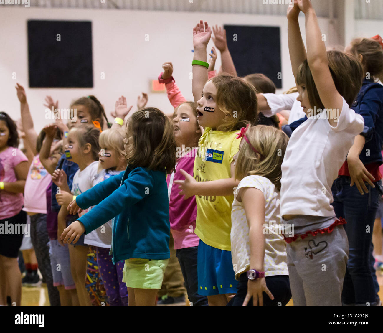 Joplin, Missouri, USA. 20th May, 2016. Children at Joplin Family YMCA's Fit Kids Army listen to KC Ambassador Shawn Barber's instructions on various warm-up stretches. Here they reach upwards after an exercise of bending downward and touching their toes. These warm-ups occur at the beginning of the Play 60 Clinic hosted by the Chiefs Community Caring Team. The Kansas City Chiefs' Play 60 Clinic promotes health and wellness for children and youth. © Serena S.Y. Hsu/ZUMA Wire/Alamy Live News Stock Photo