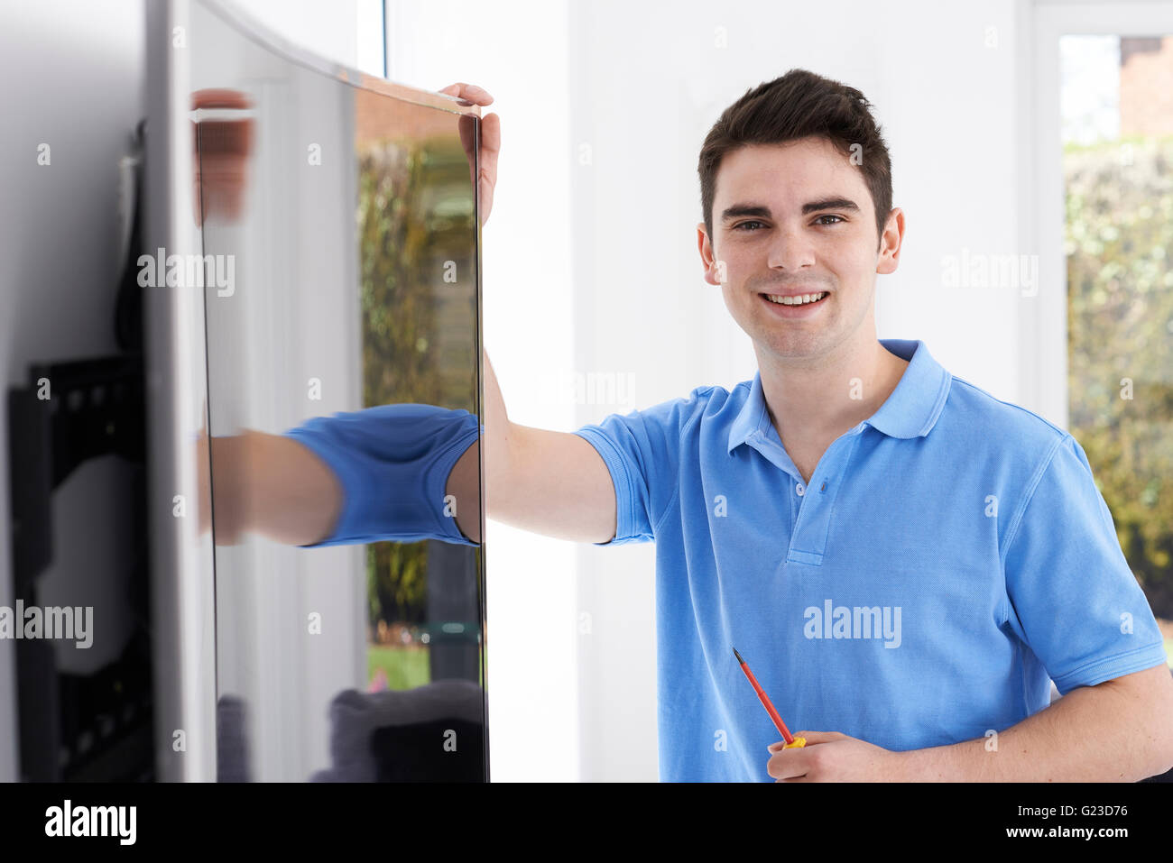 Engineer Fitting Curved Screen Television In Home Stock Photo