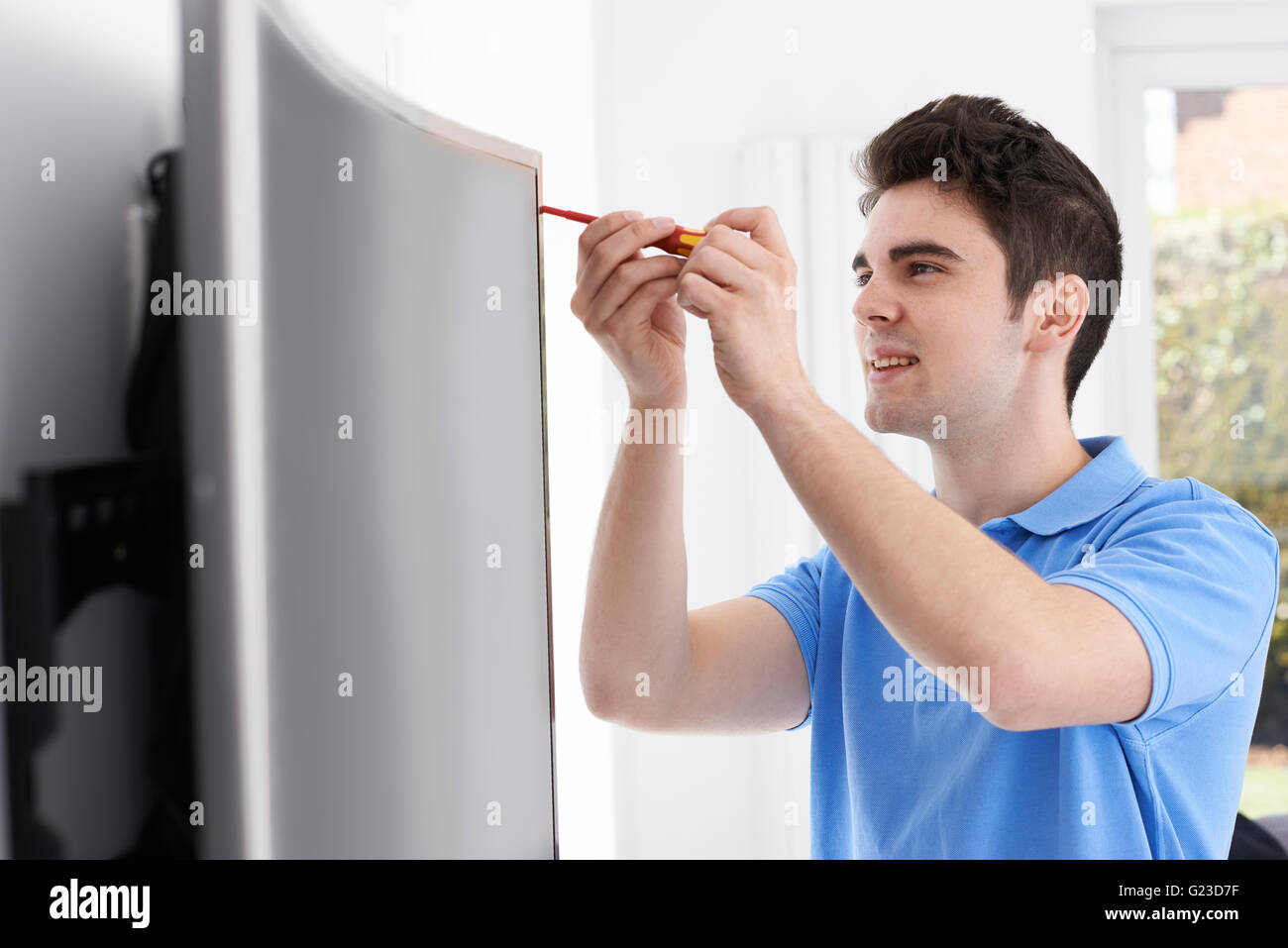 Engineer Fitting Curved Screen Television In Home Stock Photo