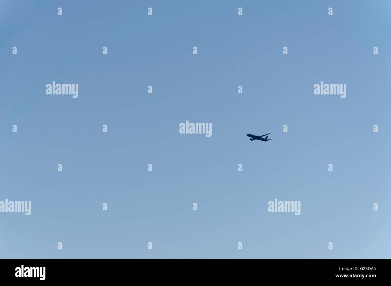 A distant jet airplane climbing in clear blue skies in Australia Stock Photo