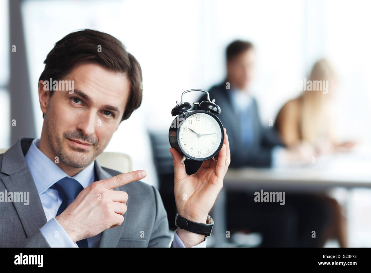 Businessmen in office with alarm clock, deadline concept Stock Photo