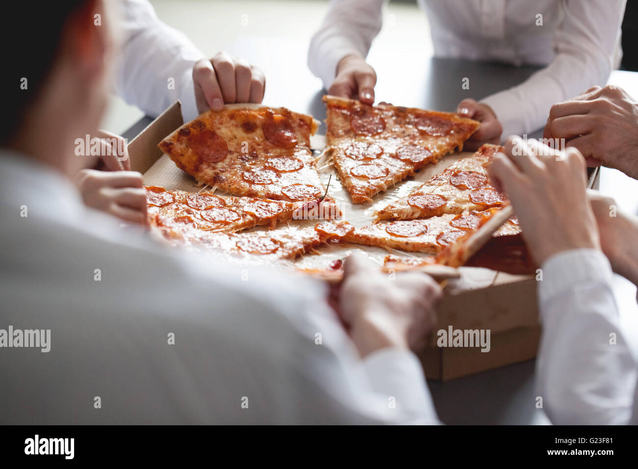 Business team eating pizza in office sitting around the table Stock Photo