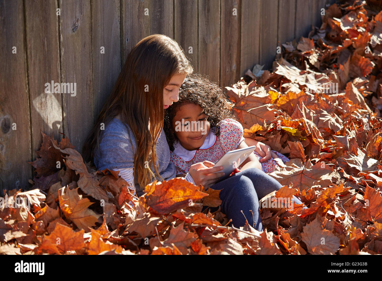 Kid girls friends playing tablet pc in autumn leaves park mixed ...
