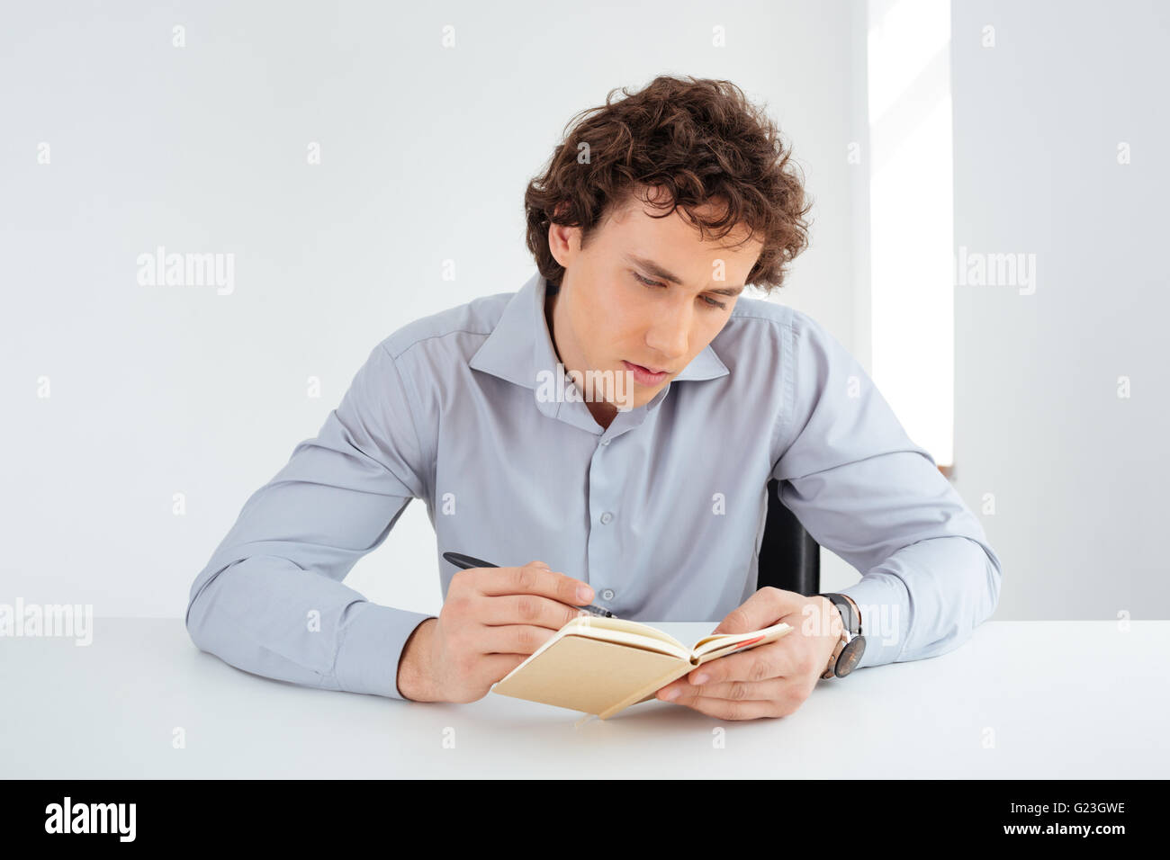 Young businessman writing notes in notebook in office Stock Photo