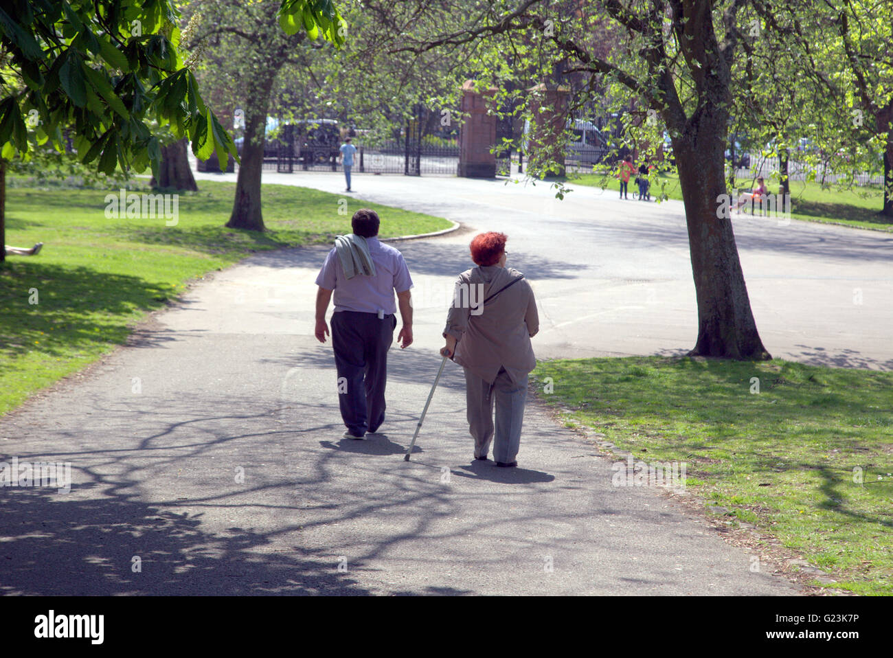 Middle aged or old couple with walking stick walking in Kelvingrove Park Glasgow, Scotland, UK. Stock Photo