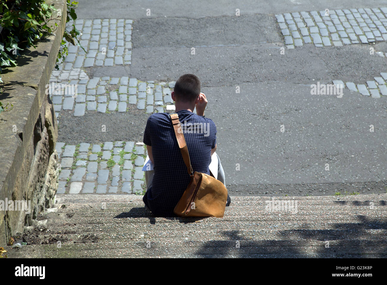 young man  or boy sitting on steps viewed from above,Glasgow, Scotland, UK Stock Photo