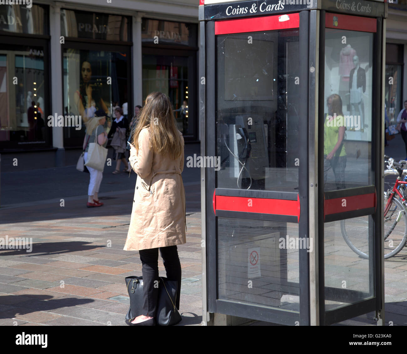 Young girl on mobile phone beside phone box Glasgow, Scotland, UK. Stock Photo