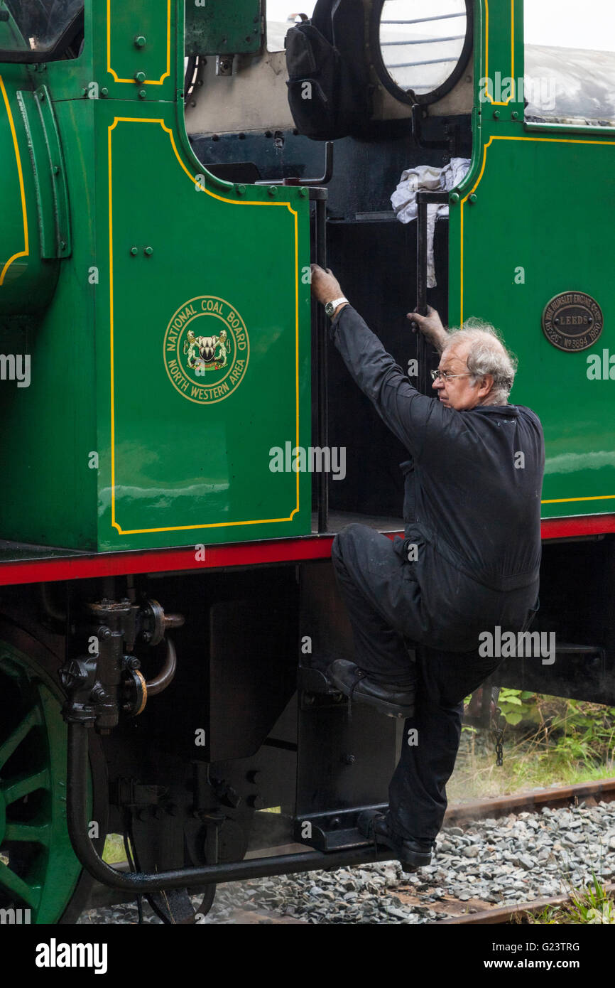Driver climbing into the cab of a saddle tank Austerity class steam engine, Nottinghamshire, England, UK Stock Photo