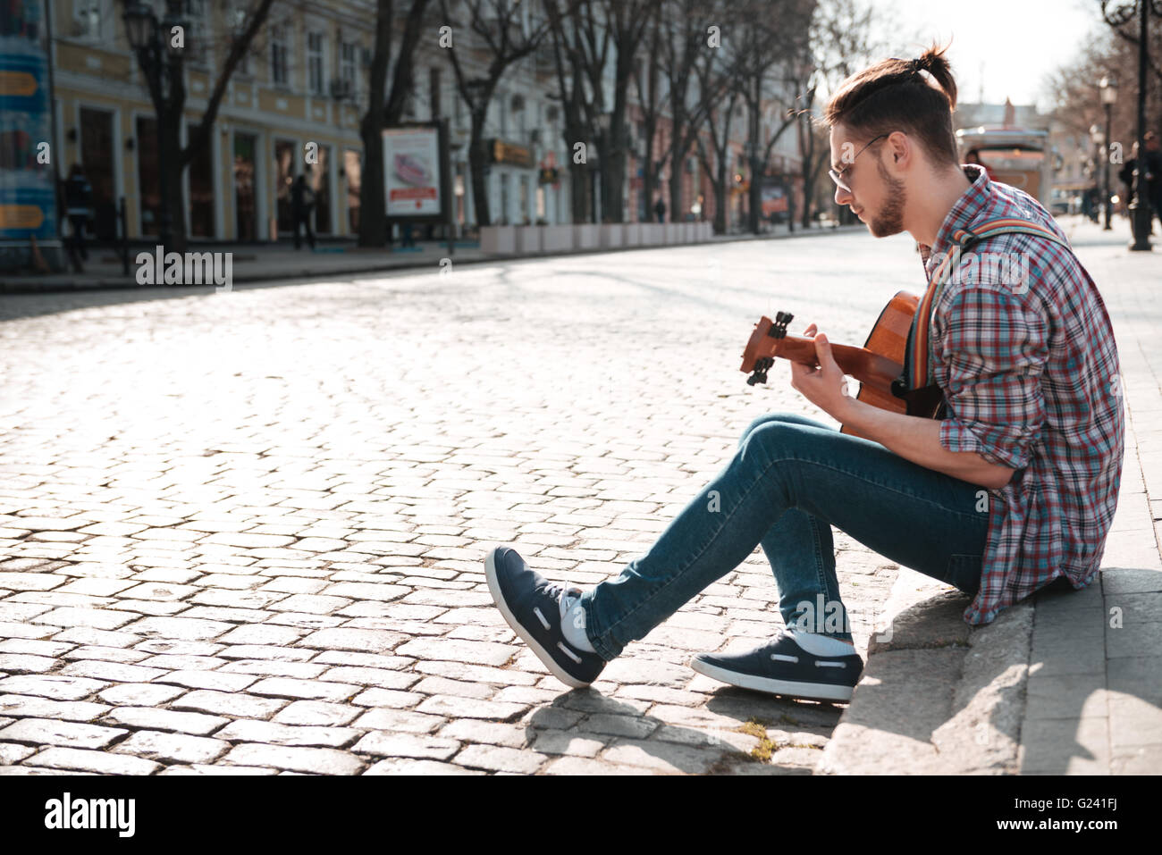 Man playing on the guitar outdoors in old city Stock Photo