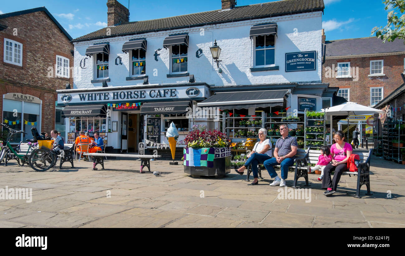 People relaxing with ice creams outside the White Horse Café in Thirsk Market Place in the town centre on a warm spring day Stock Photo