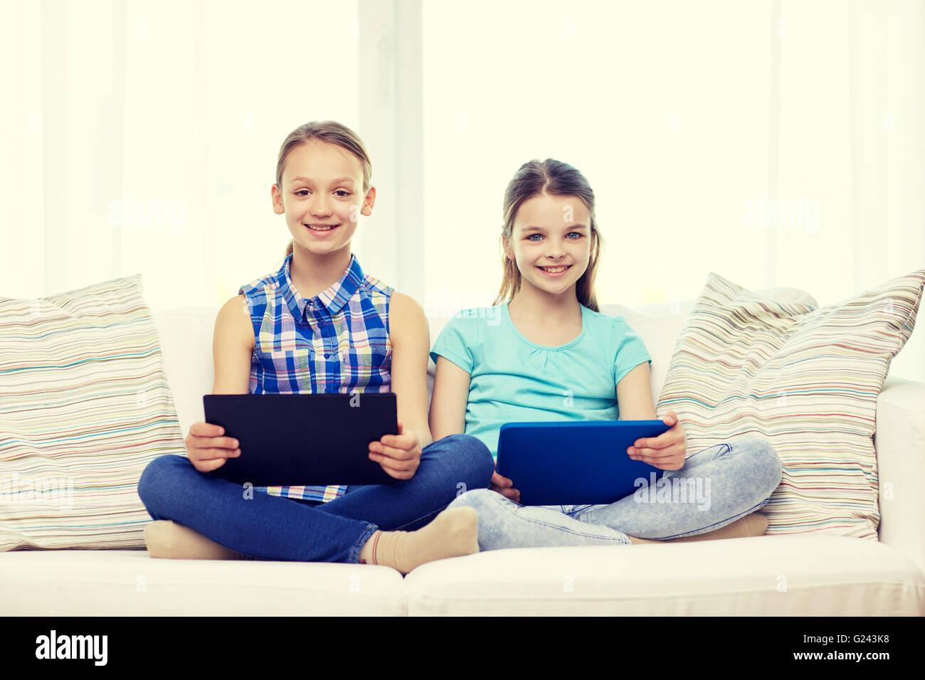happy girls with tablet pc sitting on sofa at home Stock Photo - Alamy