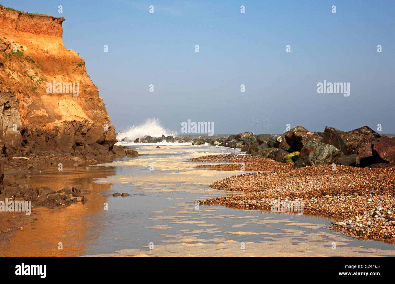 A high tide overtopping sea defences and eroding cliffs at Happisburgh ...