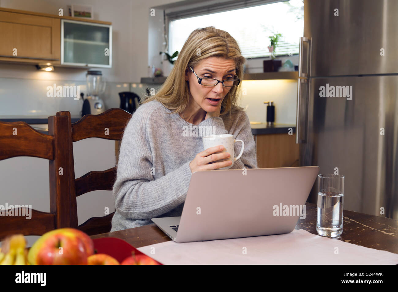 A middle aged work from home woman is happy and jubilant in front of her laptop. Medium shot. Stock Photo