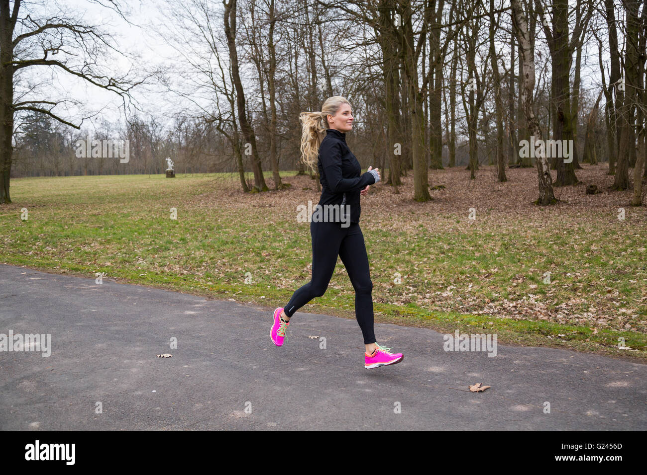 Athletic middle aged female jogging in a park. Stock Photo