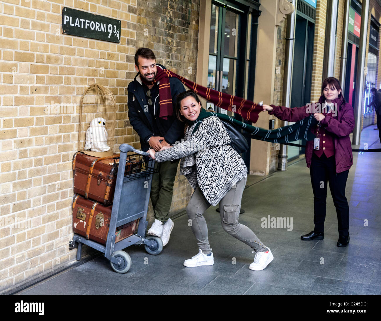 Harry Potter fans posing at the fictional platform 9 & 3/4, Kings Cross Railway Station, London, England. Stock Photo