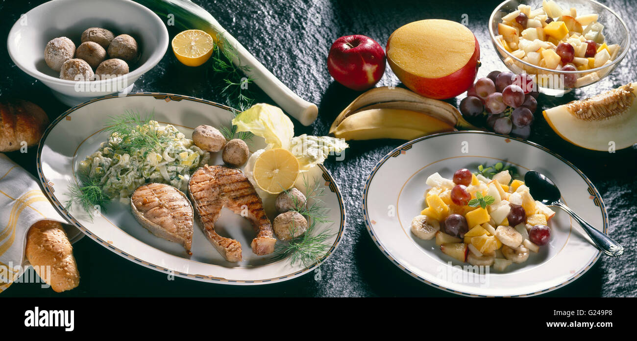 Grilled salmon, boiled potatoes, celeriac salad, fruit salad Stock Photo