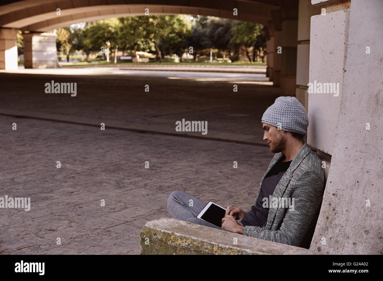 Modern young man with tablet pc touch working under a bridge with wool ...