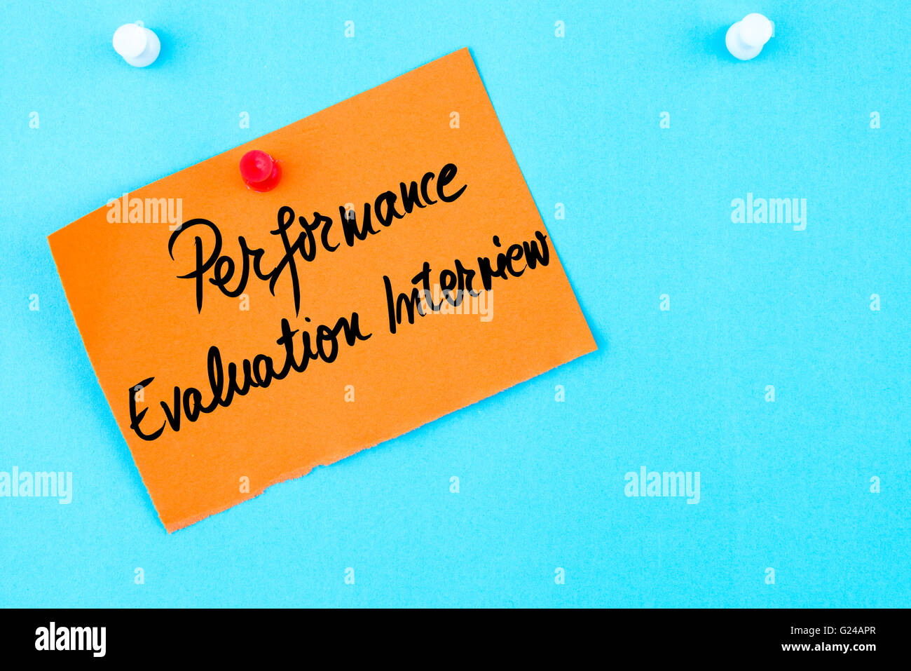 Performance Evaluation Interview written on orange paper note pinned on cork board with white thumbtack, copy space available Stock Photo