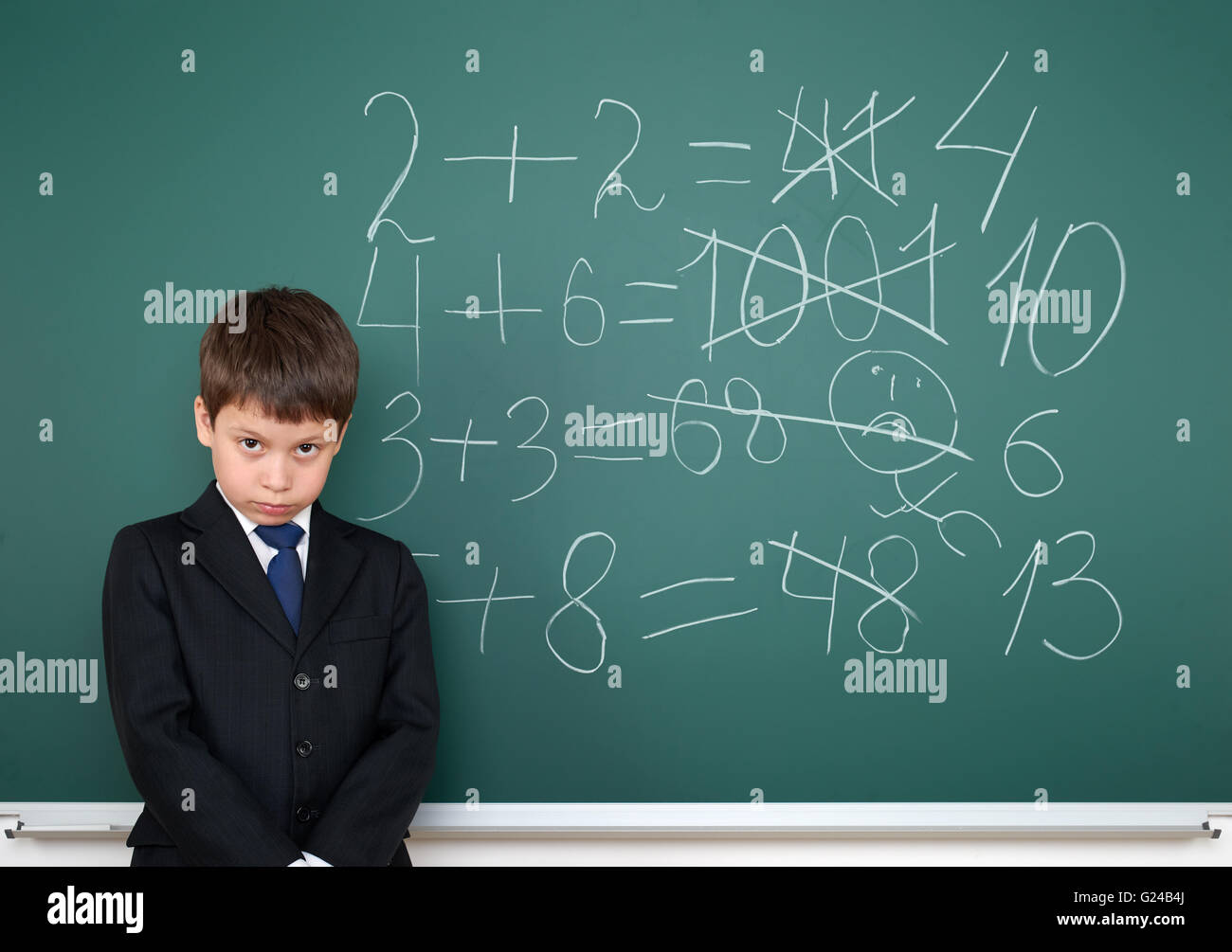 school boy decides examples math incorrect on chalkboard background, education concept Stock Photo