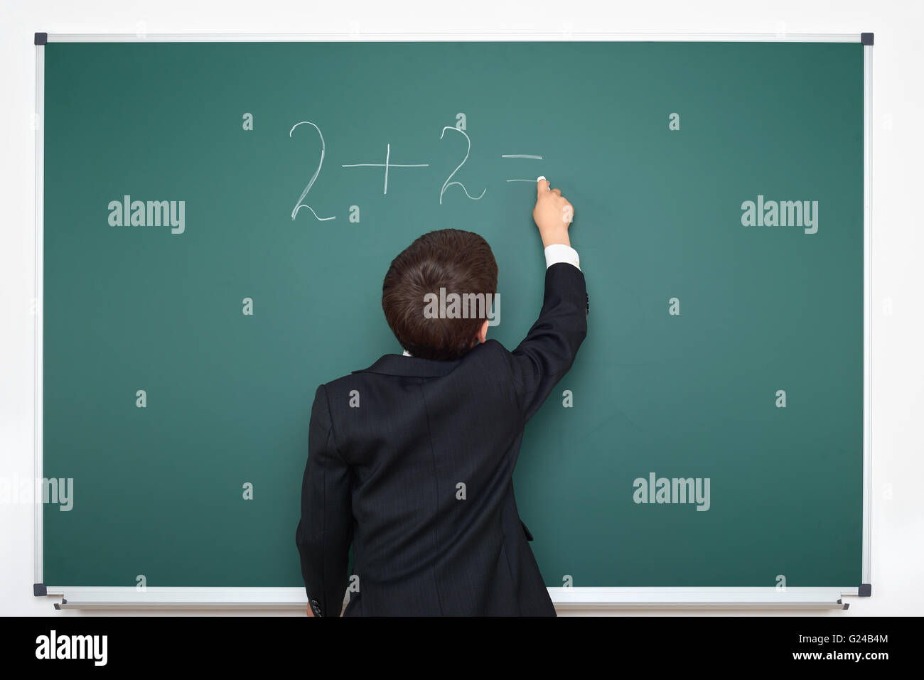 school boy decides examples math on chalkboard background, education exam concept Stock Photo