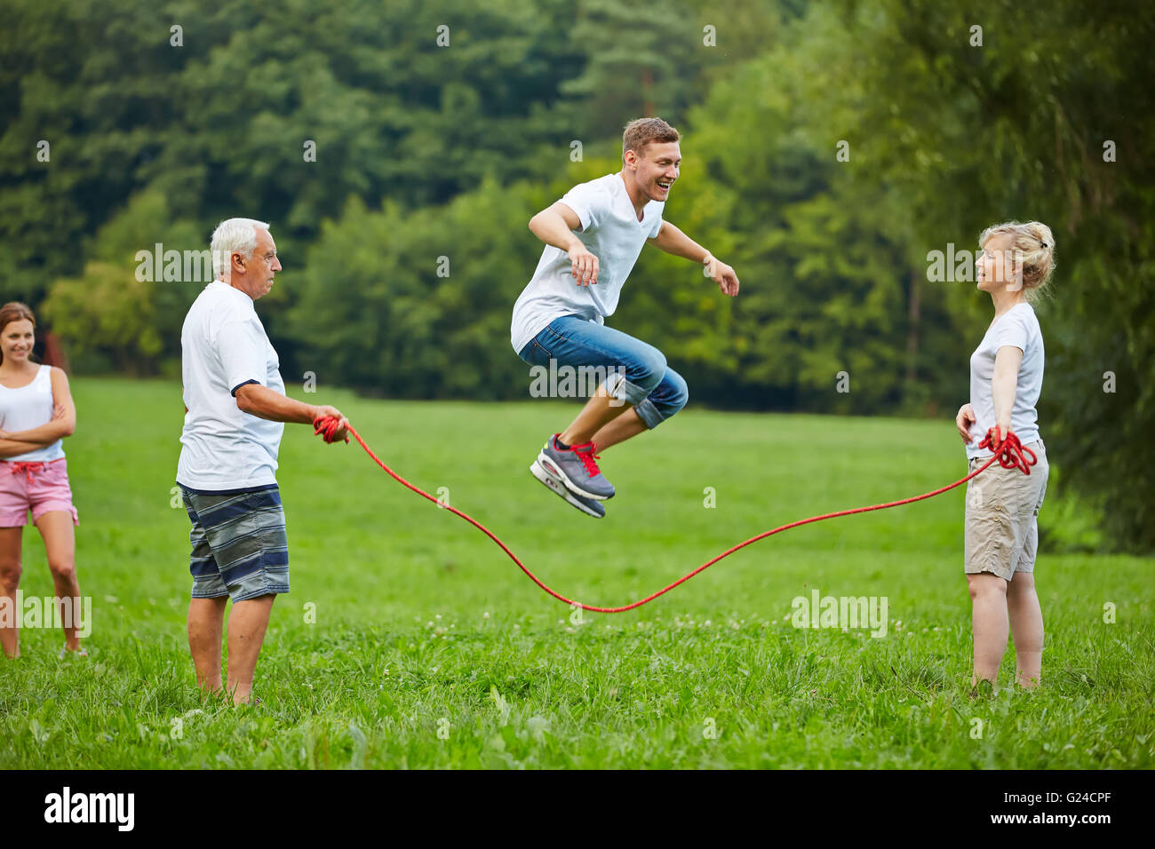 Man rope skipping with jumping rope with his family in nature Stock Photo