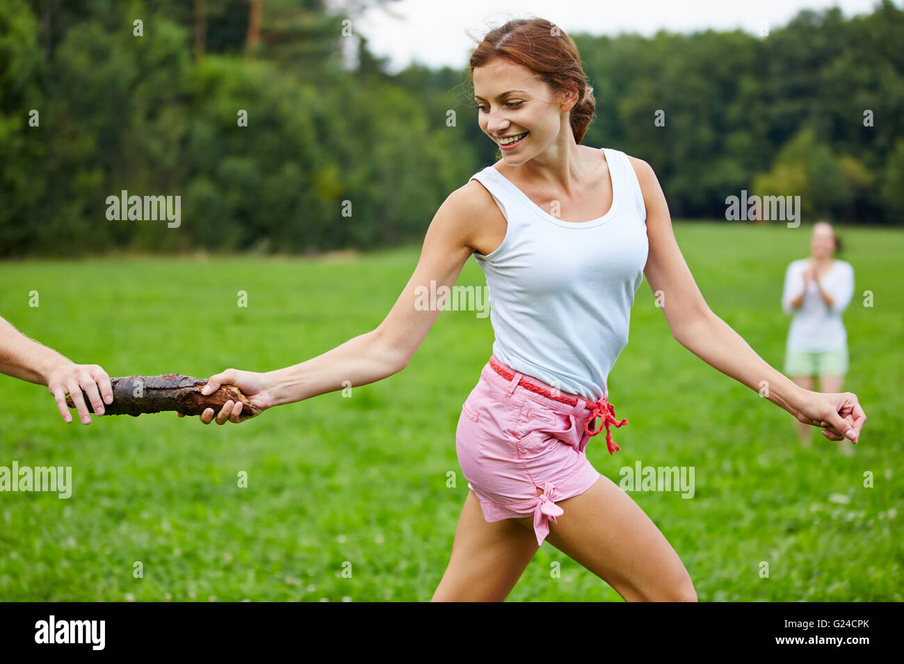 Young happy woman running a relay race in a park Stock Photo