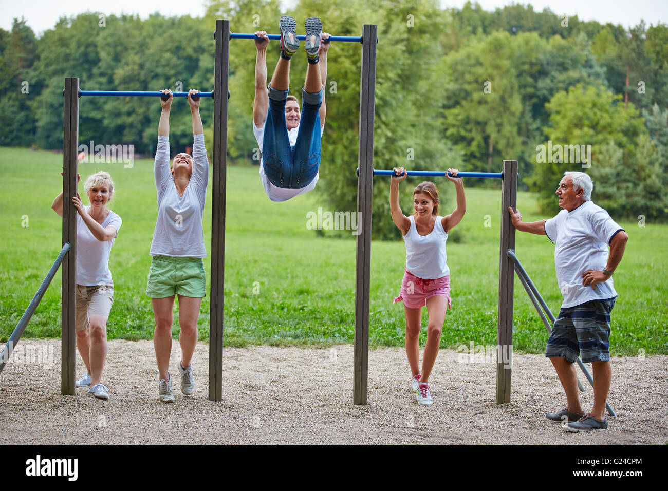 Family doing fitness training together in park at horizontal bars Stock Photo