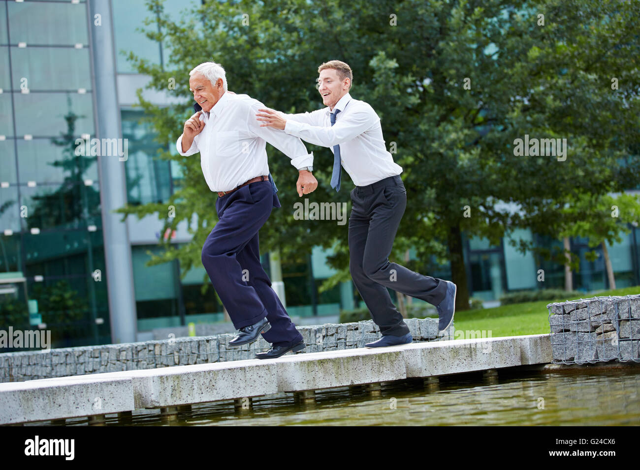 Businessman chasing senior CEO in front of the office Stock Photo - Alamy