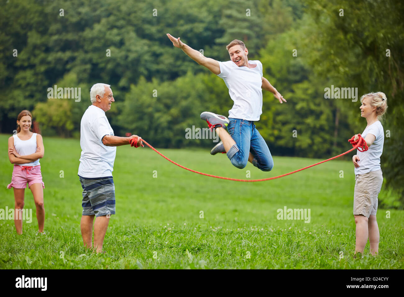 Happy man jumping high while rope skipping in nature Stock Photo