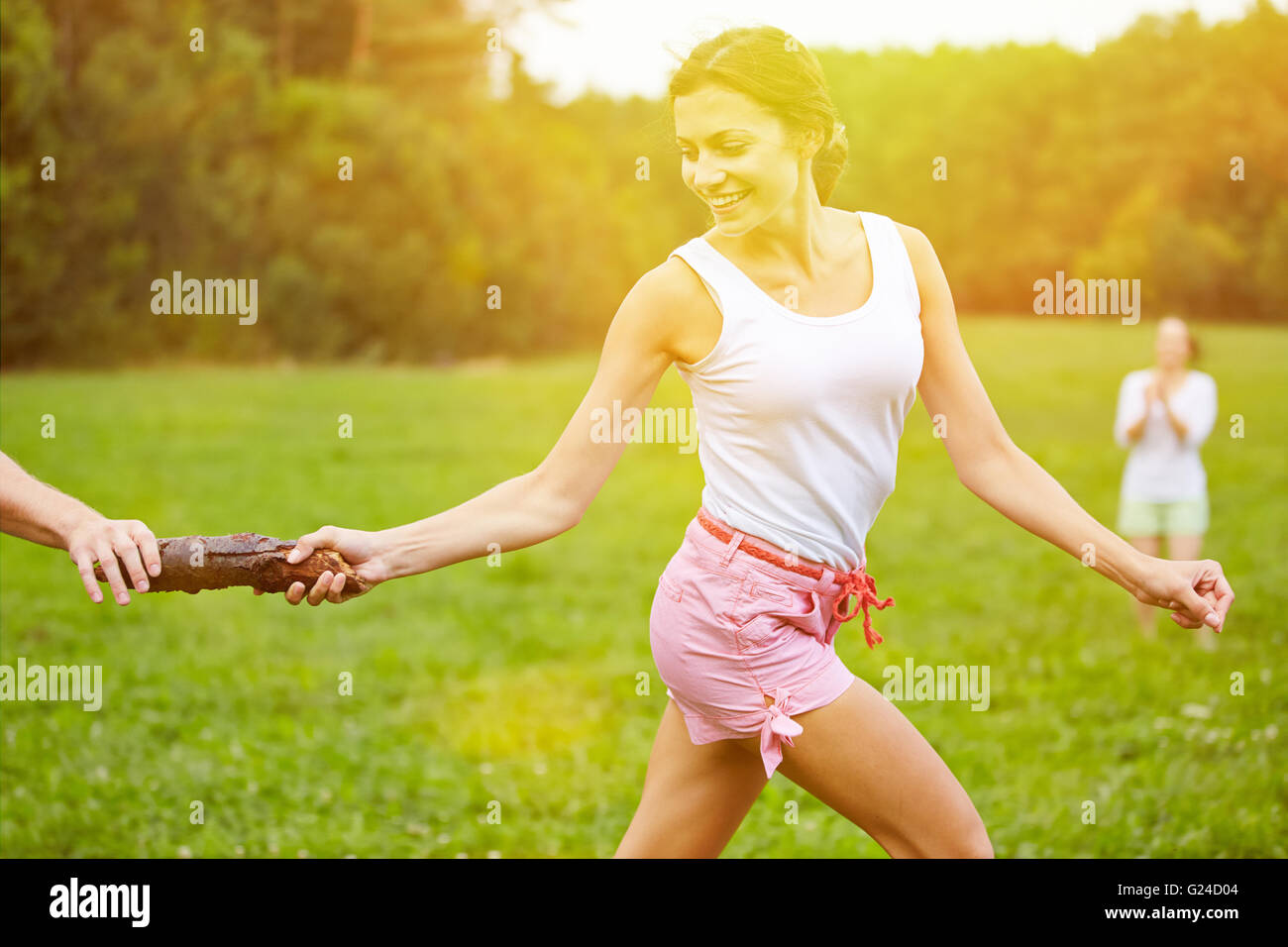 Cooperation at relay race with wooden stick as baton in summer Stock Photo